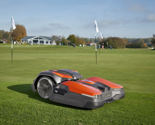 A Husqvarna CEORA mower is cutting the grass on a golf course.