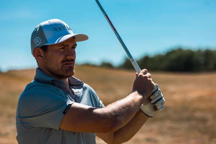 Golfspieler mit einem blauen Golfhemd, das nachhaltig hergestellt wurde.