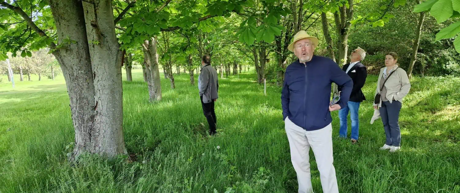 Gert Hardt steht unter Bäumen neben dem Golfplatz
