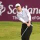 Bild auf eine Spielerin beim Chip vor einem Plakat von Scotland Golf