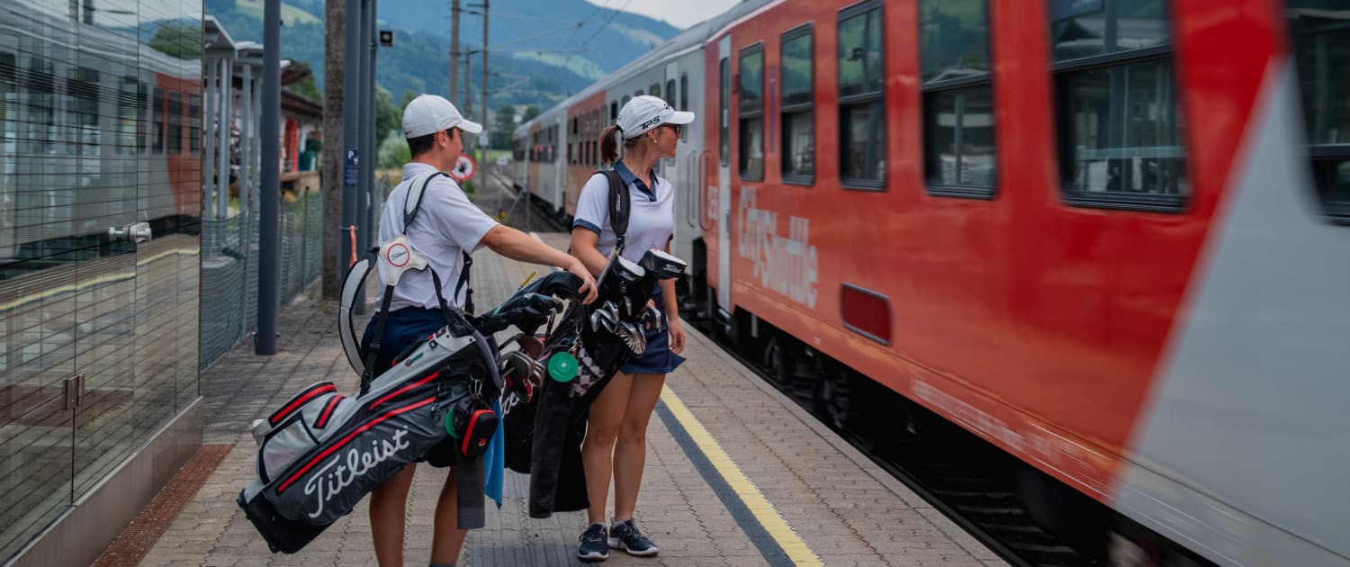 Zwei jugendliche Golfspieler steigen in einen Zug ein