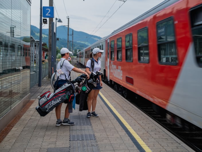 Zwei jugendliche Golfspieler steigen in einen Zug ein