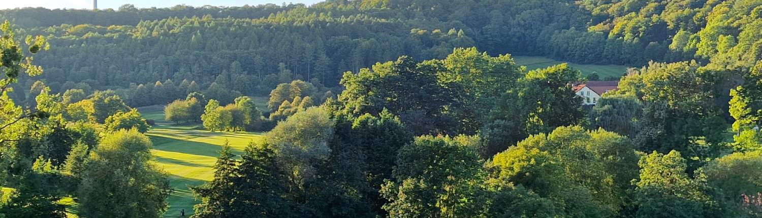 Blick auf den Golfplatz Zierenberg mit Windrädern im Hintergrund