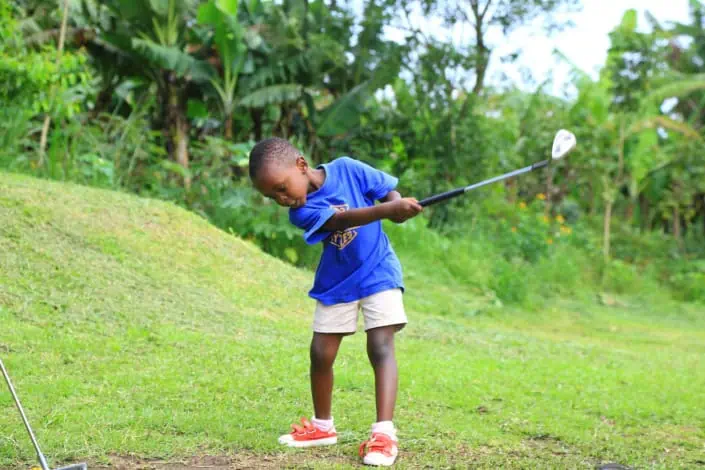 Kleiner Junge aus Uganda beim Golfspielen