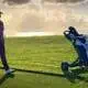 Golfer geht hinter einem Trolley mit Golfbag