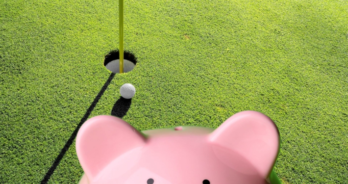 Ein Sparschwein vor einer Golfanlage